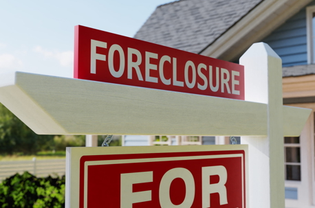 A red foreclosure sign posted outside a suburban house, illustrating legal steps to stop a foreclosure sale in California